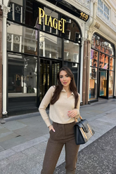 a lady in a cashmere top and a pair of brown pants